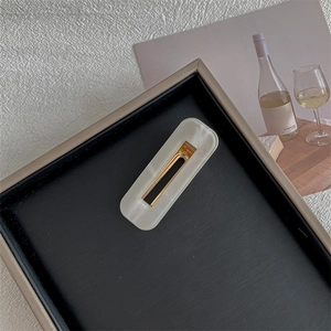 Detail of elegant rectangular cream white hair clip on a black and gold tray