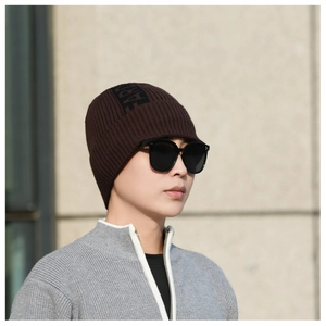 Macro detail of dark brown knit beanie showing ribbed texture and black letter jacquard
