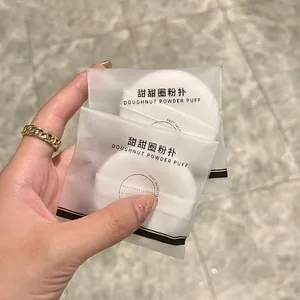 Two white cotton velour makeup puffs in individual frosted packaging with drawstrings