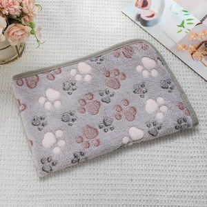 Close-up of soft flannel pet blanket with pink and grey paw prints on purple fabric