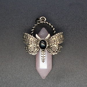 Macro shot of pink quartz hexagonal pendant with vintage bronze butterfly and black gem