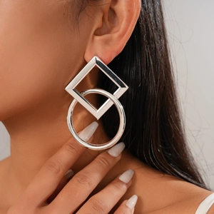 Close-up of geometric square and circle silver drop earrings worn by a female model