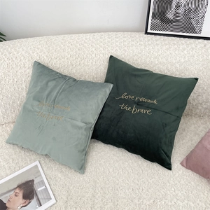 Detail of velvet pillow covers featuring gold embroidered inspirational quotes on sofa