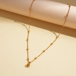 Detailed view of an 18k gold plated beaded necklace featuring a polished spherical pendant