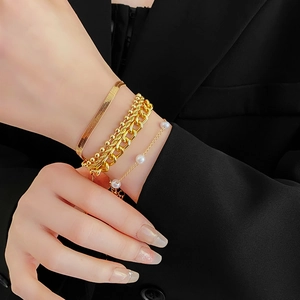 Detail of four-piece gold layered bracelets with pearls and snake chain on wrist