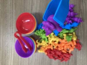 Blue tweezers picking a purple dinosaur for fine motor skill development and sorting