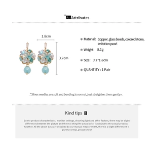Detailed view of floral earrings with light blue glass beads and imitation pearls