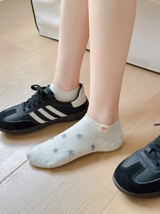 Detail of white cotton no-show socks with grey stars and MINI label worn with sneakers