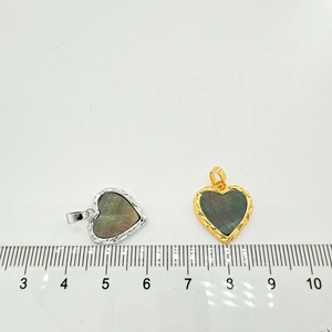 Macro view of 18K gold and silver heart pendants with natural shell and size scale