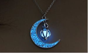 Detailed view of silver moon pendant with glowing blue luminous stone in dark environment