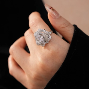 Close-up of a silver floral ring with oval zircon and pavé petals on a finger