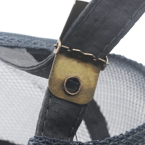 Detail of bronze metal buckle and black woven strap on quick-dry baseball cap