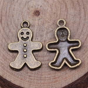 Gingerbread man pendants in bronze alloy on a wooden base for DIY jewelry making