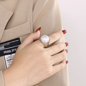 Gros plan d'une large bague en acier poli avec une grande perle sur la main d'un mannequin