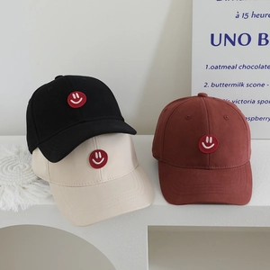 Three minimalist kids cotton baseball caps in black beige and rust red with smile patch