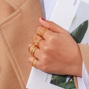 Detail of stacked gold braided and star-patterned stainless steel rings on hand
