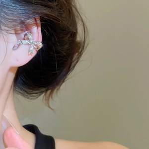 Dettaglio ravvicinato di un ear cuff a fiocco in argento con zirconi indossato da modella