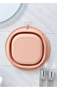 Roze opvouwbare plastic waskom hangend aan een marmeren muur met een klevende haak