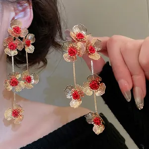 Elegant gold flower tassel earrings with red centers shown on a model for vintage style