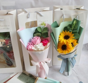Detail of pink rose and yellow sunflower soap bouquets in windowed white gift bags