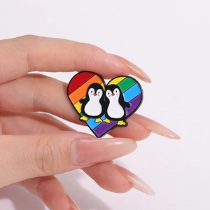 Rainbow heart enamel pin featuring cute cartoon penguins and colorful striped background