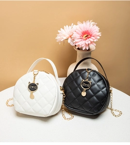 Detail of mini round quilted bags with cat charm and metal chain strap in black and white