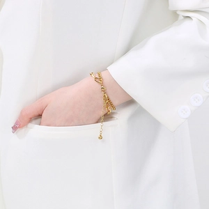 Double-layered gold stainless steel chain bracelet with adjustable clasp worn on white suit