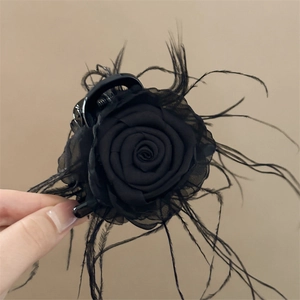 Détail d'une pince à cheveux rose foncée avec pétales en soie et plumes noires