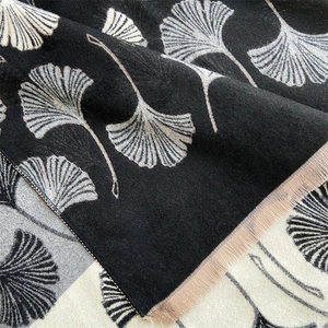 Close-up of winter cashmere scarf featuring elegant beige ginkgo leaf pattern and tassels