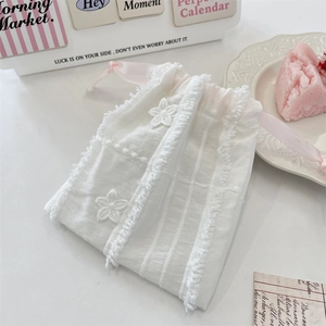 Close-up of white lace pouch with floral embroidery and pink ribbon drawstring