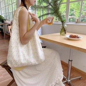 Detailed view of cream floral canvas tote bag featuring embroidered flowers in a cafe
