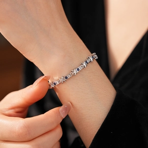 Dettaglio del bracciale a maglie X argentato con zirconi blu e bianchi luccicanti