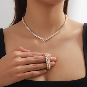Macro shot of gold V-shaped necklace and ring set with square zircon on a model