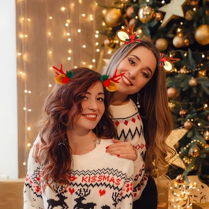 Close-up of women wearing festive reindeer antler headbands with bells and bows for Christmas