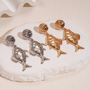 Modern textured metal fish earrings in gold and silver finishes on a stone plate