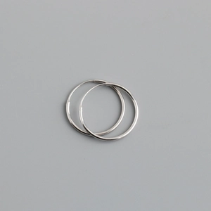 Detailed close-up of a pair of minimalist S925 sterling silver hoop earrings on gray background