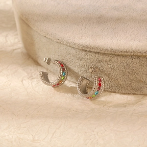 Detailed view of silver C-shaped stainless steel earrings with rainbow colored rhinestones