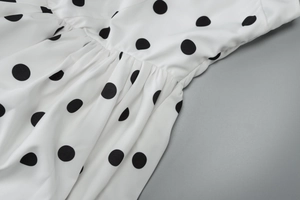 Close-up of black polka dot print fabric with delicate pleated waist seam details