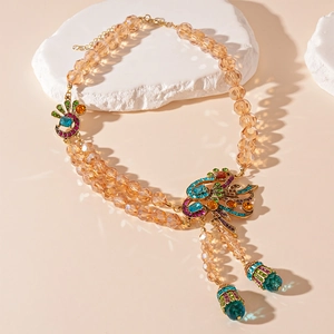 Detail of double-layer champagne bead necklace with a crystal peacock pendant and tassels