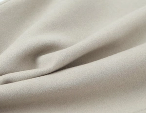 Gros plan sur le tissu couleur avoine montrant une texture douce et un aspect laine chaud