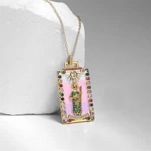 Golden tarot-style pendant necklace with colorful cubic zirconia on stone display