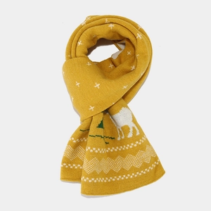 Detailed close-up of ginger yellow knit scarf with white reindeer and snowflake patterns