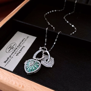 Detail of vintage silver double heart pendants with emerald green stone and small diamonds