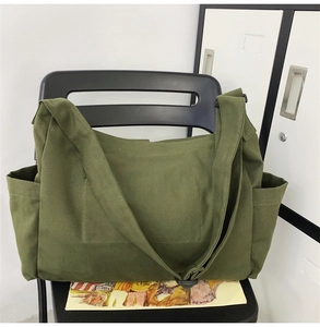Detail view of large army green canvas messenger bag with wide strap on chair