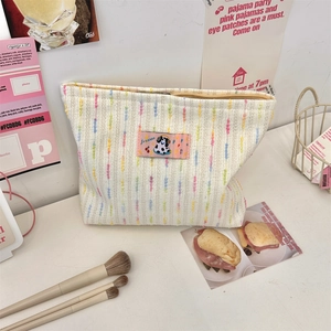 Détail d'une trousse de maquillage tissée avec rayures arc-en-ciel et patch chien
