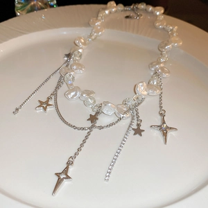 Gros plan de perles baroques et pendentifs étoile en argent sur plateau céramique