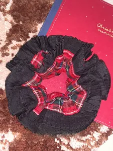 Detail of red and green plaid scrunchie with black pleated ruffle on a gift box