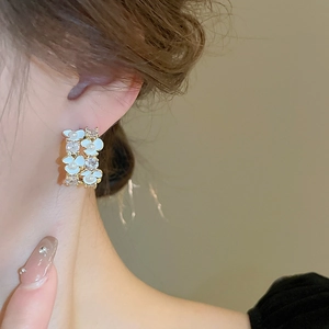 Detailed close-up of French style flower stud earrings with white enamel and blue petals