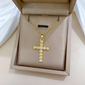 Close-up of golden titanium steel cross necklace with cubic zirconia in a jewelry box