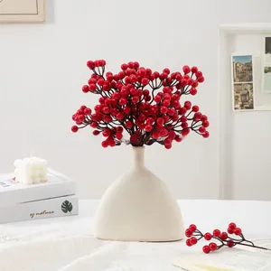 Close-up of vibrant red holly berries in a white ceramic vase for home festive decoration